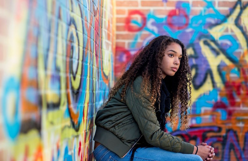 Woman leaning against a wall covered in graffiti.