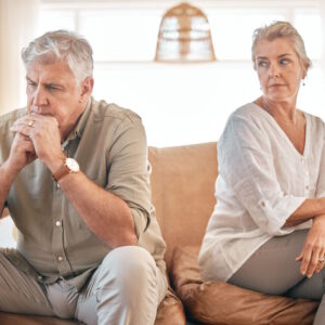 Senior couple, divorce and disagreement in conflict, fight or argument on living room sofa at home. Elderly woman and frustrated man in depression, cheating affair or toxic relationship in the house