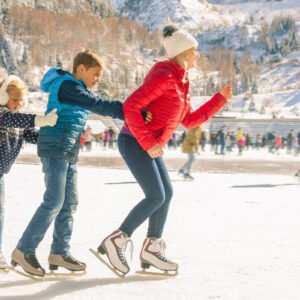 Happy family outdoor ice skating at rink. Mother and children has winter activities. Mom, kids. Medeo stadium. Almaty.