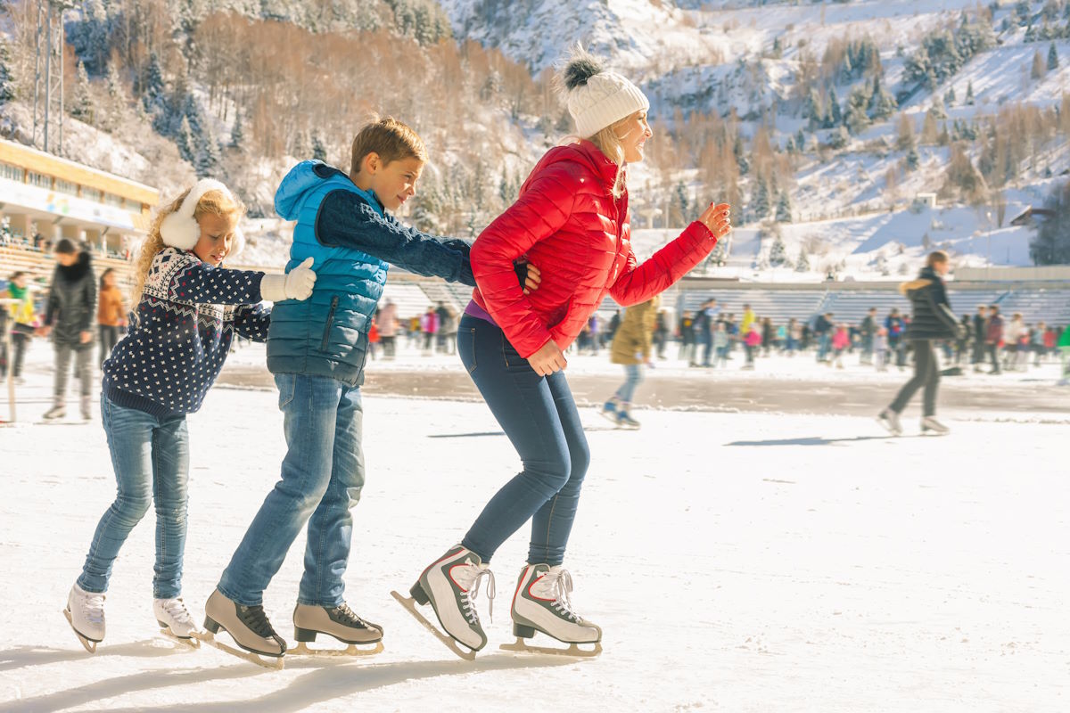 Happy family outdoor ice skating at rink. Mother and children has winter activities. Mom, kids. Medeo stadium. Almaty.