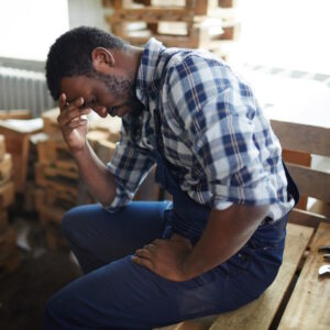 Photo of man sitting in workshop showing signs of stress